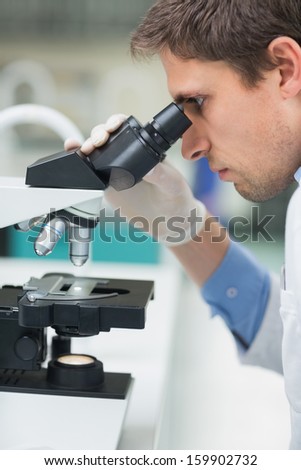 Close-up side view of a male scientific researcher using microscope in the laboratory