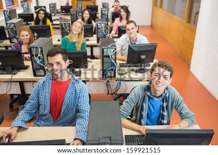 Group portrait of smiling students using computers in the college computer room