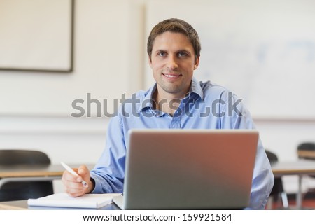 Handsome mature student learning and sitting in classroom while smiling at camera