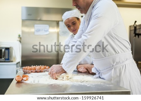 Serious head chef kneading dough in professional kitchen