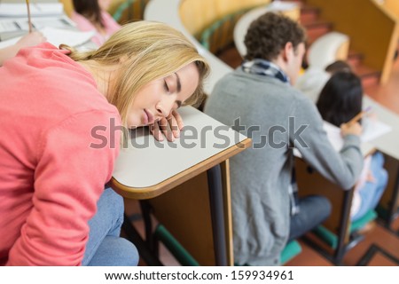 Female sleeping with students sitting in the college lecture hall
