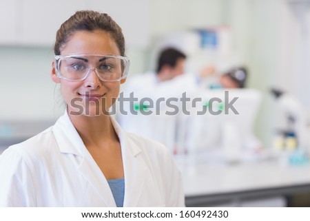 Close-up of a female researcher with colleagues in the background at the laboratory