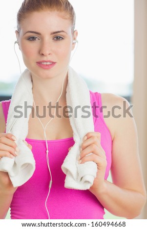 Portrait of a young woman with towel around neck listening to music in fitness studio