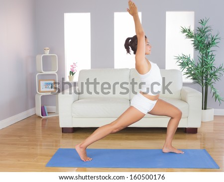 Sporty slim woman practicing yoga pose for stretching her body in her living room