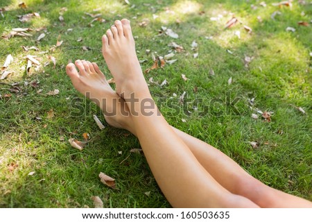 Close up of crossed legs of a woman lying on the grass in a park on a sunny day