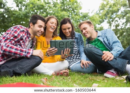 Group of young college students using tablet PC in the park