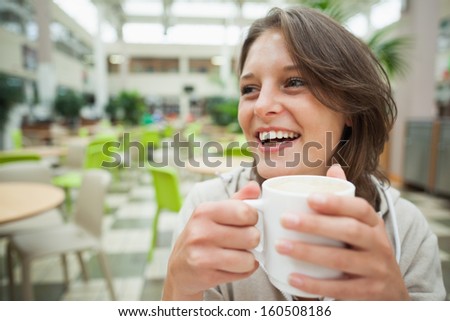 Close-up of a cheerful female student drinking coffee in the cafeteria