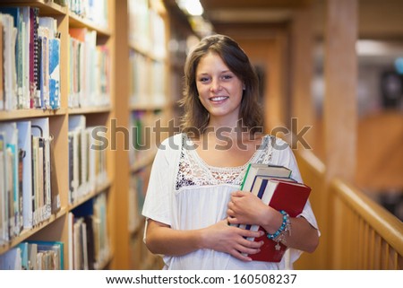 Portrait of a smiling female student standing in the library