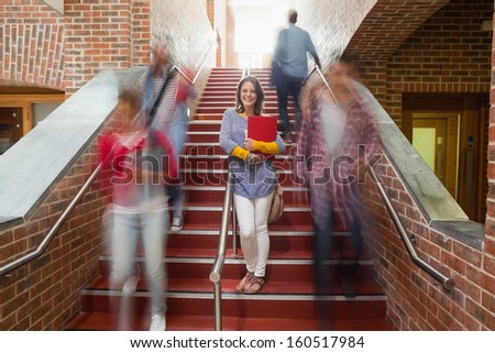 Casual smiling student standing on stairs in college