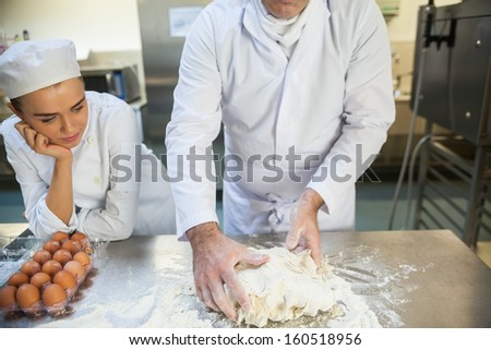 Head chef kneading dough in professional kitchen