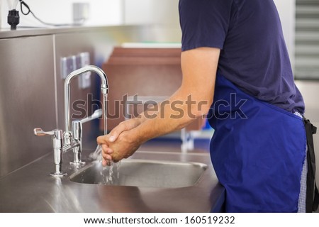 Kitchen Porter Washing His Hands In Professional Kitchen
