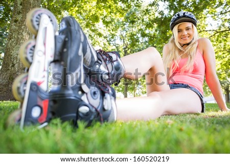 Casual attractive blonde wearing roller blades and helmet in a park