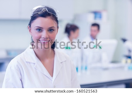 Portrait of a female researcher with colleagues in the background at laboratory