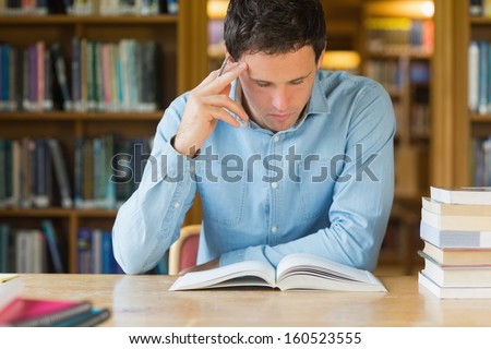 Serious mature male student studying at desk in the library