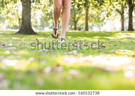 Close up of female feet wearing sandals walking on grass in a park on a sunny day