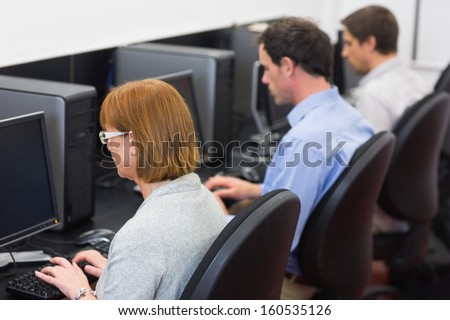 Rear view of mature students using computers in the computer room