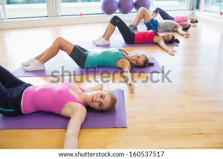 Side view of fitness class lying on exercise mats in row at fitness studio
