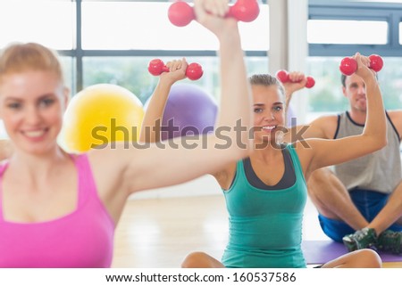 Close-up of fitness class and trainer lifting dumbbells in the gym