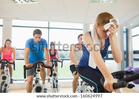 Determined And Tired People Working Out At An Exercise Bike Class In Gym