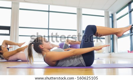 Side view of class stretching on mats at yoga class in fitness studio