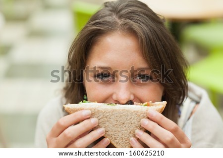 Close-Up Portrait Of A Smiling Female Student With Sandwich In The Cafeteria