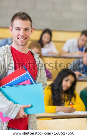 Portrait of a smiling male with students sitting at the college lecture hall