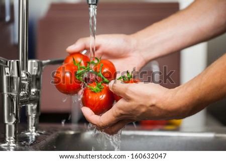 Kitchen Porter Washing Tomatoes In Professional Kitchen