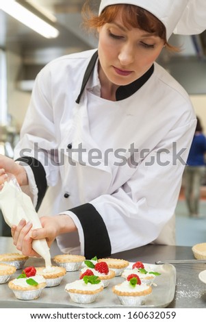 Pretty concentrated head chef preparing dessert in professional kitchen