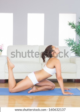 Pretty woman in sportswear doing yoga in her living room on an exercise mat