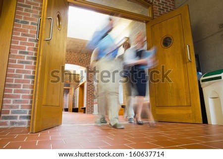 Low angle view of a group of blurred people walking through open doors