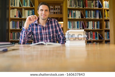 Portrait of a smiling mature male student studying at desk in the library