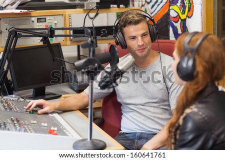 Attractive content radio host interviewing a guest in studio at college