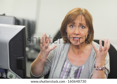 Outraged mature student sitting in front of computer looking at camera