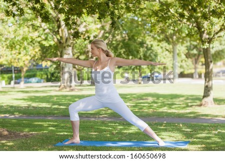 Side view of beautiful fit woman stretching in yoga pose in a park