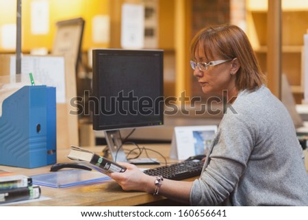 Female librarian holding a book reading the cover before scanning it