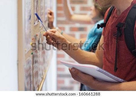 Casual students searching something on notice board in college Casual students searching something on notice board in college