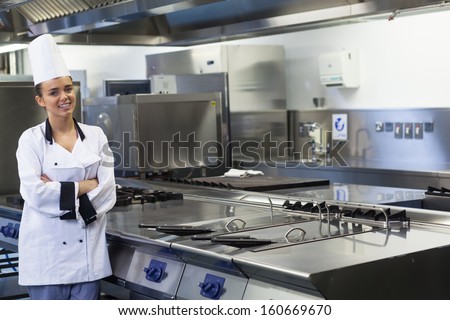 Young smiling chef standing next to work surface in professional kitchen
