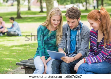 Group of young college students using tablet PC in the park