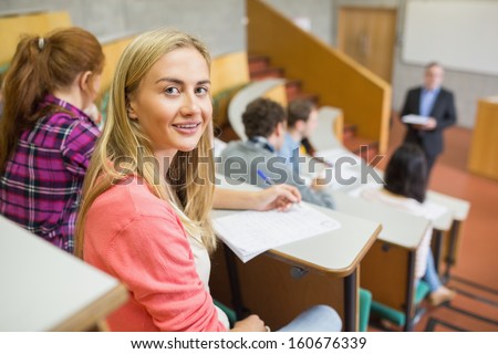 Portrait of a smiling female with students and teacher at the college lecture hall