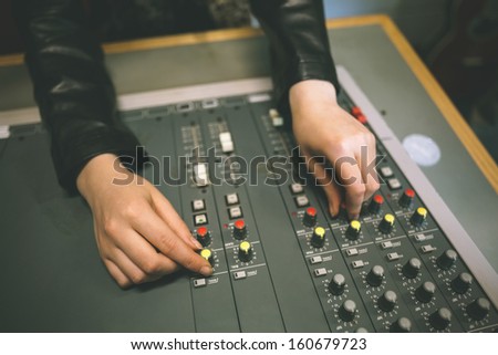 Close up of female hands turning up volume in radio studio at college