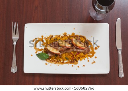 Overhead view of couscous dish with meat and red wine on wooden table