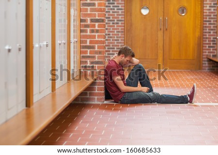 Handsome student in pain having a headache in school