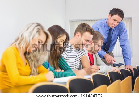 Side view of teacher with college students in row at the classroom