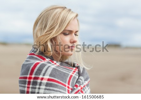 Close up side view of a young woman covered with blanket at the beach
