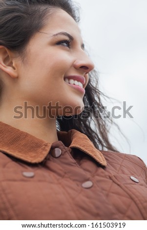 Close up of a cute smiling young woman in stylish brown jacket on the beach