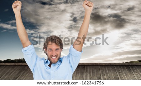 Composite image of happy man celebrating success with arms up