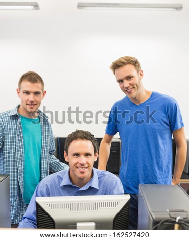 Portrait of a smiling teacher and young students using computer in the computer room