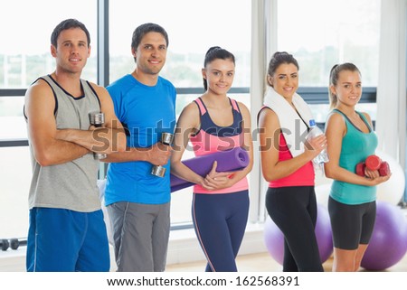 Portrait of a group of fitness class standing in row at a bright exercise room