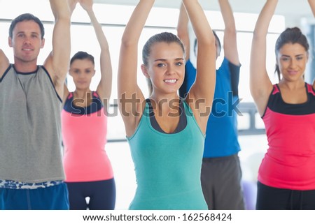 Portrait of sporty people stretching up hands at yoga class in fitness studio