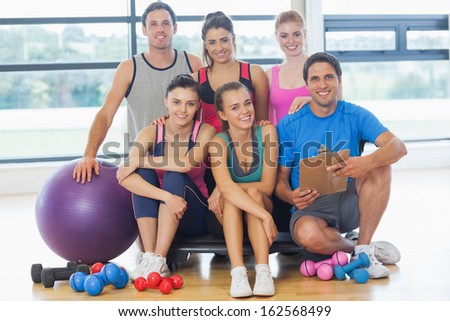 Portrait of an instructor with fitness class sitting in a bright exercise room